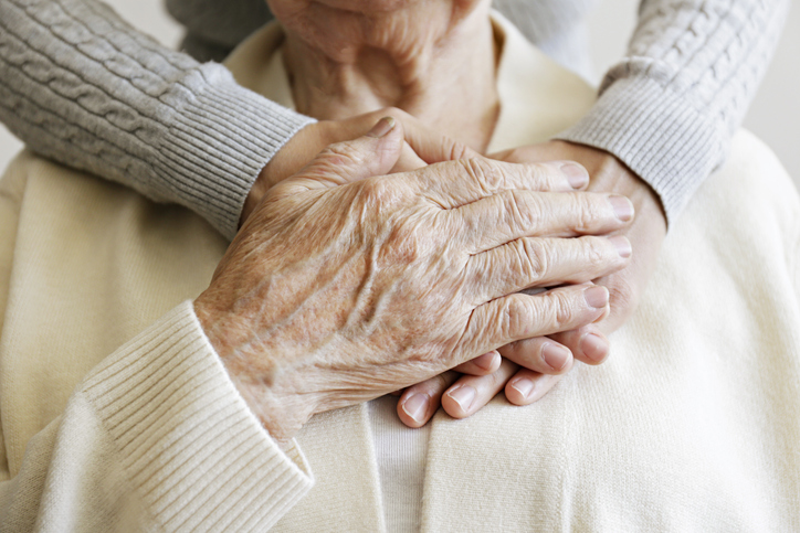 Mature female in elderly care facility gets help from hospital personnel nurse. Senior woman, aged wrinkled skin & hands of her care giver. Grand mother everyday life. 