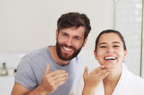 Portrait, skincare and couple in bathroom, smile and cleaning with grooming, care and wellness. Treatment, home and man with woman, happiness or healthy skin with beauty, cosmetics or morning routine